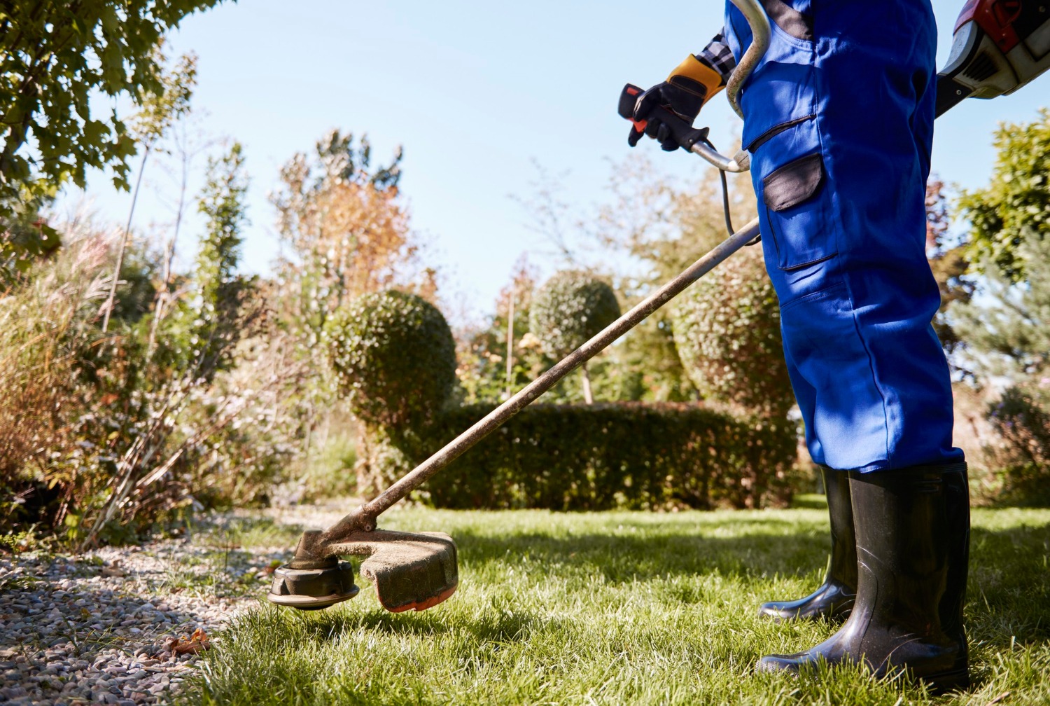gardener-with-weedwacker-cutting-grass-garden